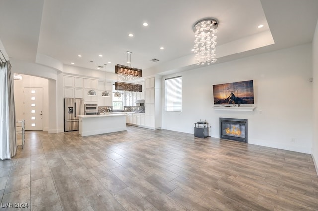 unfurnished living room with a notable chandelier and light wood-type flooring