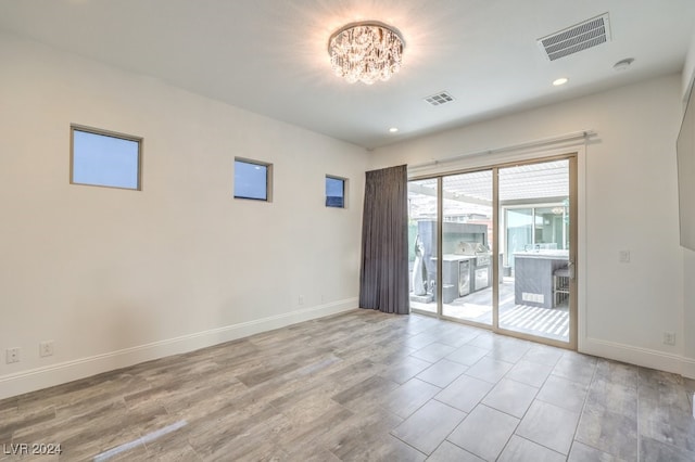 empty room with light wood-type flooring and a chandelier