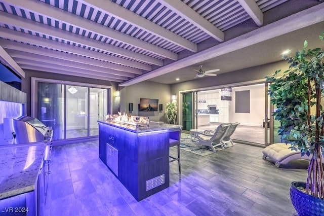 kitchen featuring a center island, hardwood / wood-style flooring, beam ceiling, a kitchen bar, and ceiling fan