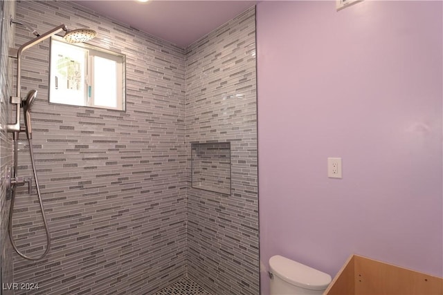 bathroom featuring a tile shower and toilet