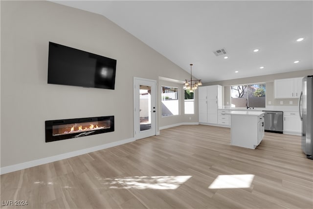 kitchen featuring white cabinets, hanging light fixtures, a kitchen island, appliances with stainless steel finishes, and vaulted ceiling