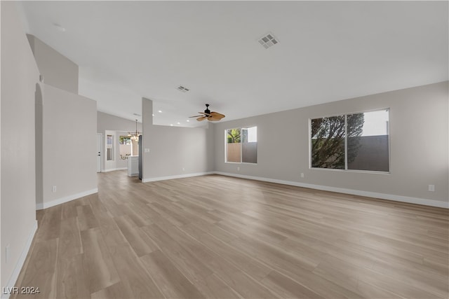 unfurnished living room with vaulted ceiling, light wood-type flooring, and ceiling fan with notable chandelier