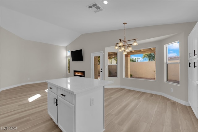 kitchen featuring lofted ceiling, white cabinets, a kitchen island, light wood-type flooring, and pendant lighting