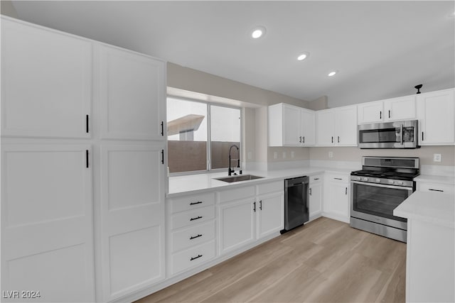 kitchen featuring lofted ceiling, sink, white cabinetry, and stainless steel appliances