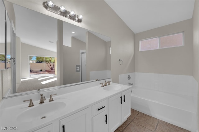 bathroom with a bathing tub, lofted ceiling, vanity, and tile patterned flooring