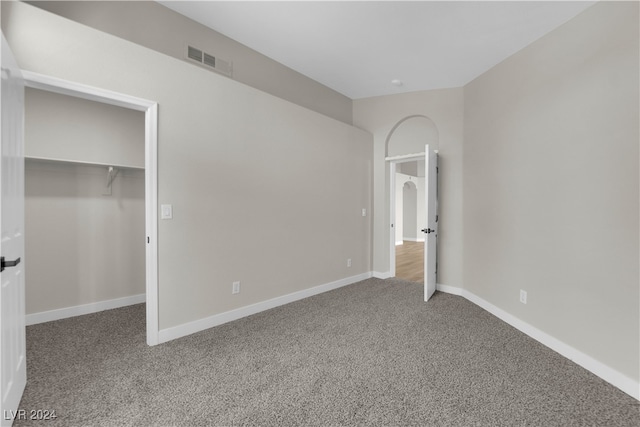 unfurnished bedroom with a walk in closet, carpet floors, and a closet