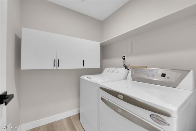 laundry area with light hardwood / wood-style flooring, washer and dryer, and cabinets