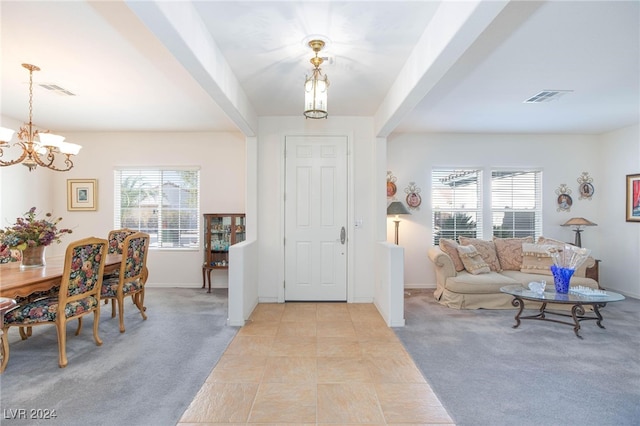 entrance foyer with light colored carpet, an inviting chandelier, and plenty of natural light