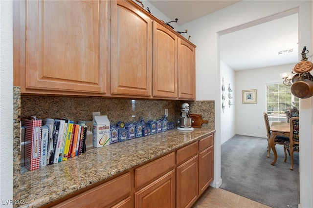 kitchen featuring decorative backsplash, light stone countertops, a chandelier, and light tile patterned floors