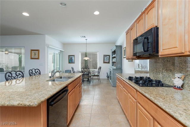 kitchen featuring an island with sink, black appliances, decorative backsplash, sink, and hanging light fixtures