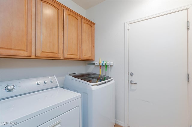 clothes washing area featuring washing machine and clothes dryer and cabinets