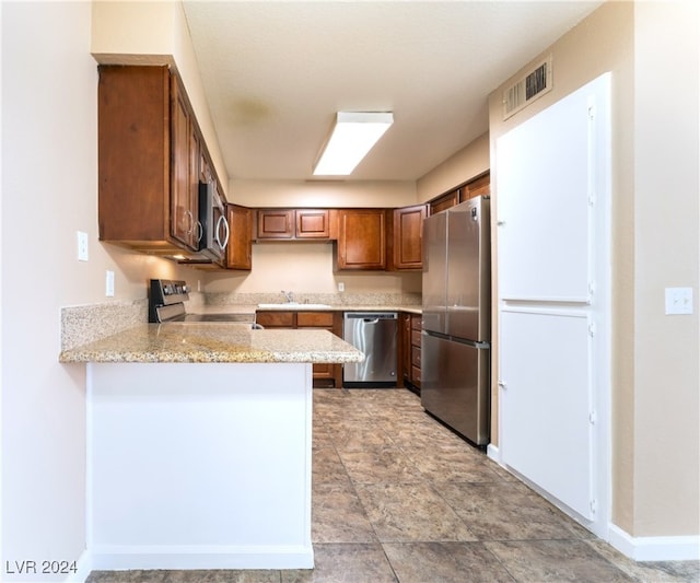 kitchen featuring appliances with stainless steel finishes, light stone countertops, kitchen peninsula, and sink