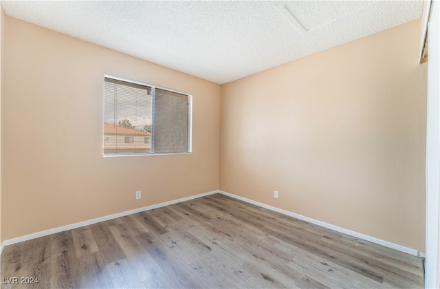 unfurnished room with a textured ceiling and light hardwood / wood-style flooring