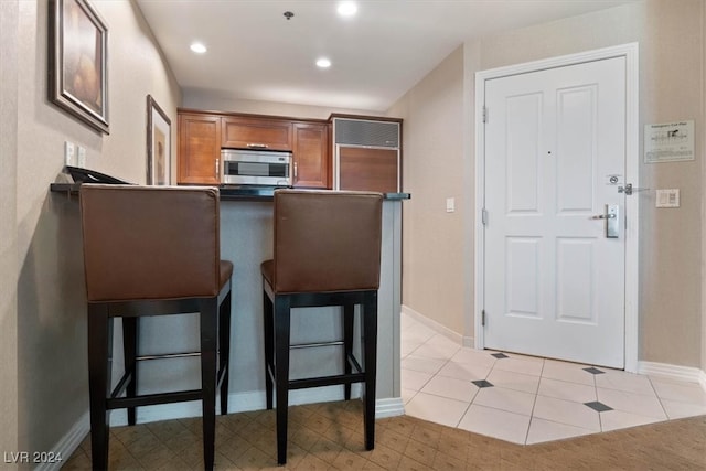 kitchen featuring kitchen peninsula, light tile patterned floors, and a breakfast bar area