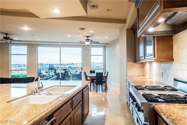 kitchen featuring high end stove, tasteful backsplash, sink, custom range hood, and ceiling fan