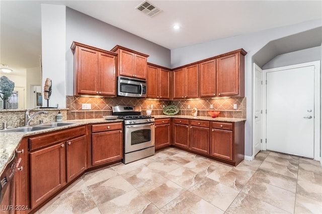 kitchen featuring light stone counters, appliances with stainless steel finishes, tasteful backsplash, and sink