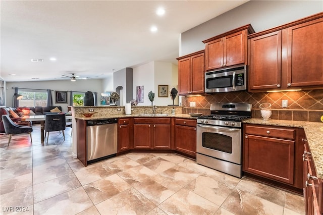 kitchen featuring vaulted ceiling, light stone counters, stainless steel appliances, ceiling fan, and sink