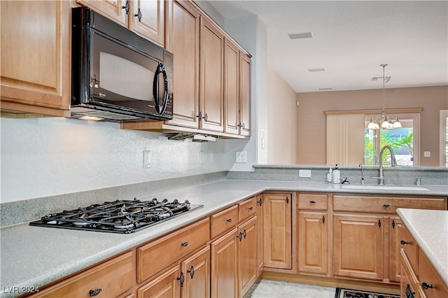 7457 Widewing Dr, North Las Vegas, NV 89084 - kitchen with black microwave, a sink, gas cooktop, light countertops, and a chandelier