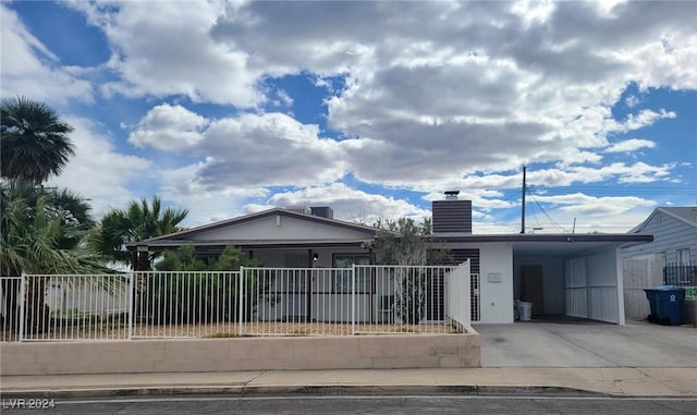 view of front facade featuring driveway, a chimney, an attached carport, fence, and stucco siding