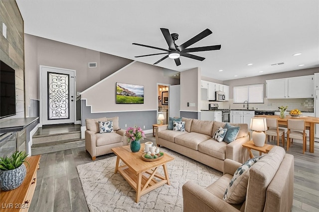 living room featuring light hardwood / wood-style floors, ceiling fan, and sink