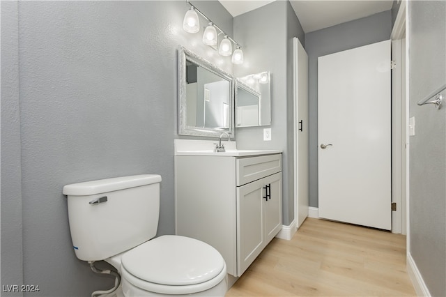 bathroom featuring wood-type flooring, vanity, and toilet