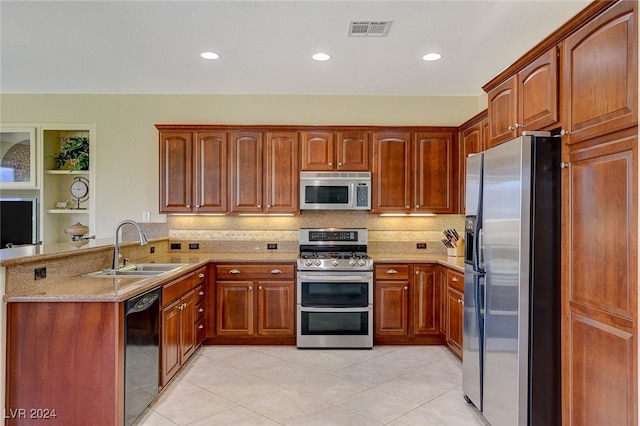 kitchen featuring light stone counters, sink, kitchen peninsula, stainless steel appliances, and backsplash