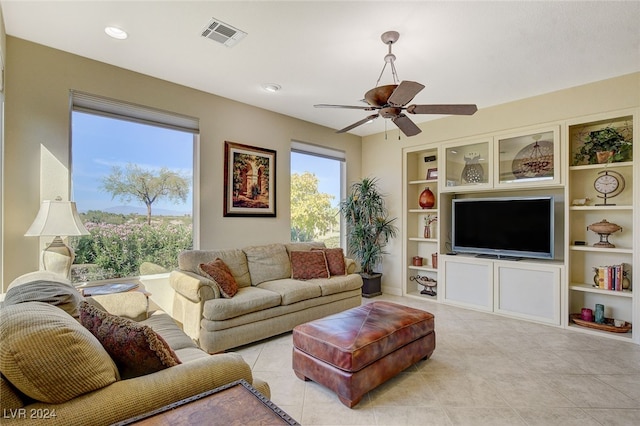 tiled living room with ceiling fan and built in features