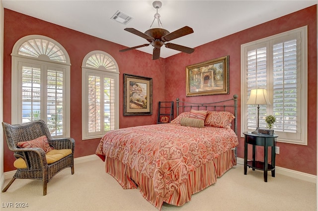 carpeted bedroom with ceiling fan and multiple windows