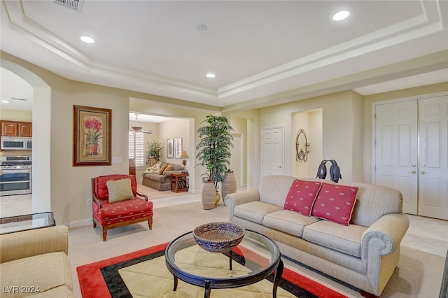 living room with a raised ceiling and light colored carpet