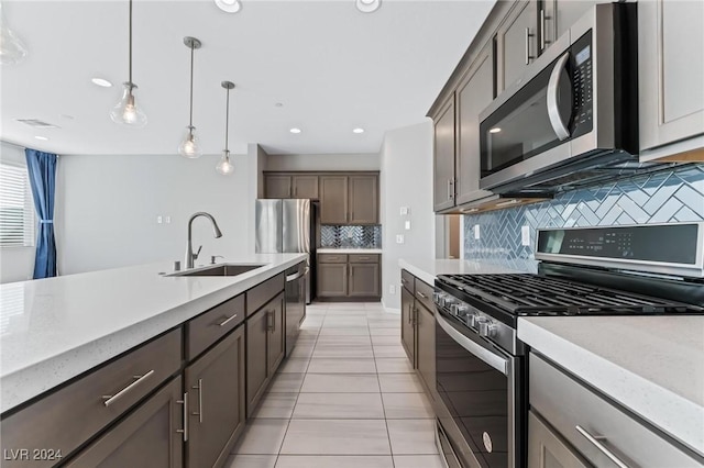 kitchen with hanging light fixtures, sink, light tile patterned floors, appliances with stainless steel finishes, and tasteful backsplash