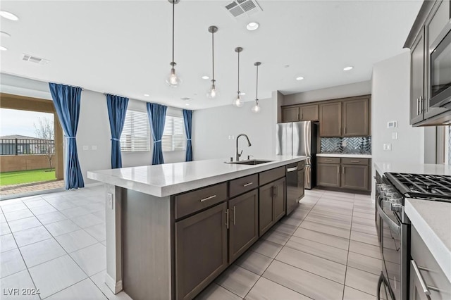 kitchen featuring an island with sink, stainless steel appliances, a healthy amount of sunlight, and sink