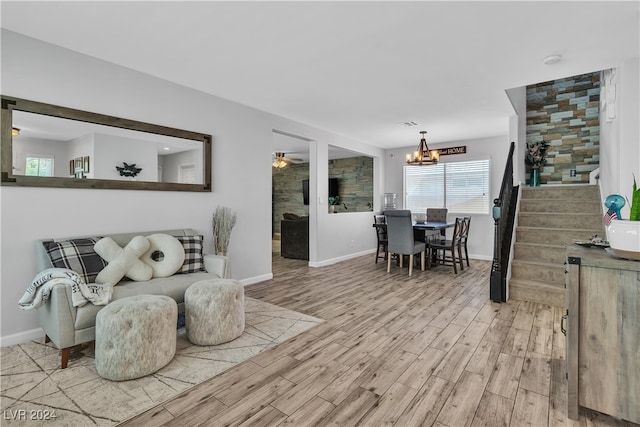 living room featuring ceiling fan with notable chandelier and light wood-type flooring