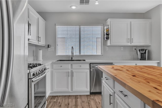 kitchen featuring white cabinets, sink, light hardwood / wood-style flooring, appliances with stainless steel finishes, and butcher block counters