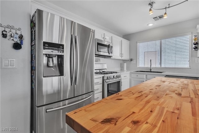 kitchen featuring white cabinets, stainless steel appliances, sink, and wood counters