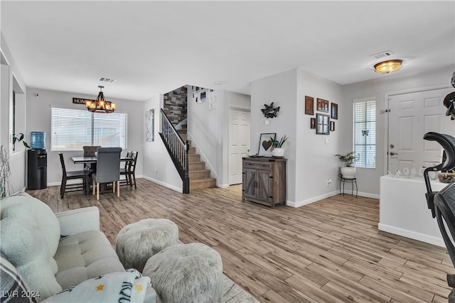 living room with light hardwood / wood-style floors and a notable chandelier