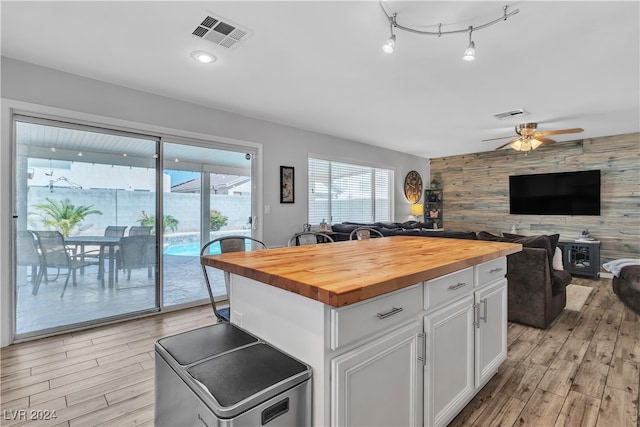 kitchen with ceiling fan, white cabinets, wood walls, butcher block countertops, and light wood-type flooring