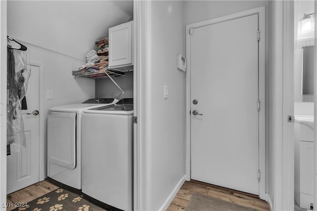 laundry area with light hardwood / wood-style flooring, independent washer and dryer, and cabinets