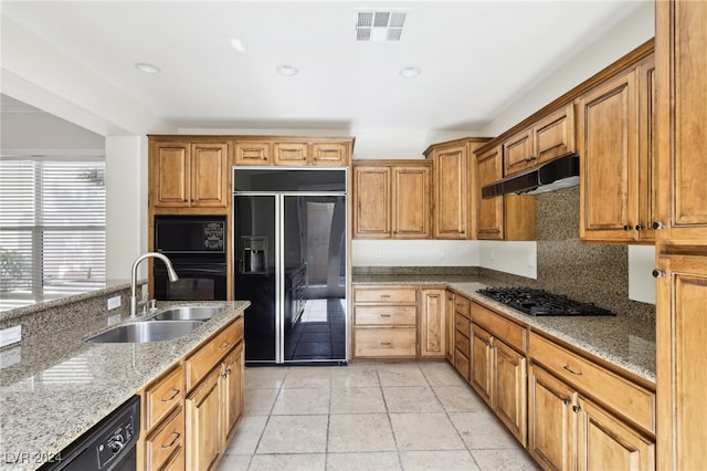 kitchen featuring decorative backsplash, light stone counters, light tile patterned flooring, black appliances, and sink