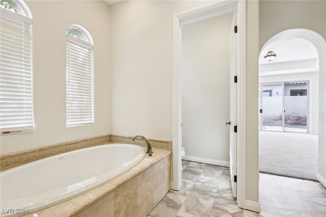 bathroom featuring toilet and tiled tub