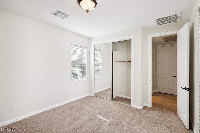 unfurnished bedroom featuring light colored carpet and a closet