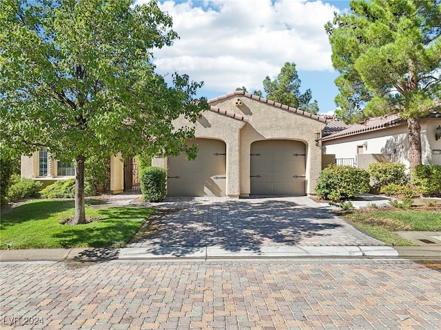 mediterranean / spanish home with a garage and a front lawn