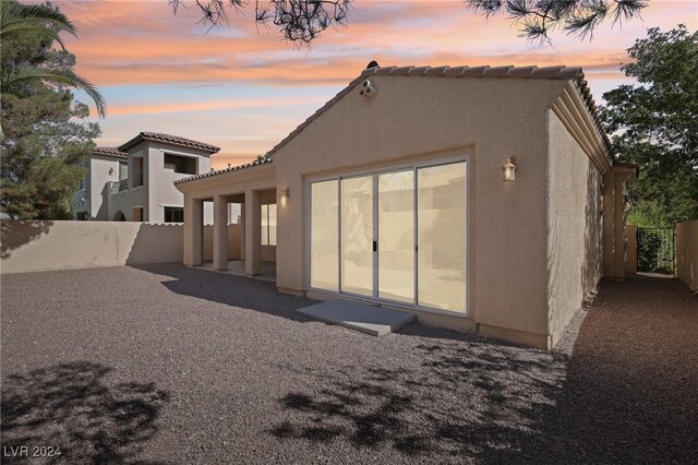 back house at dusk featuring a patio area