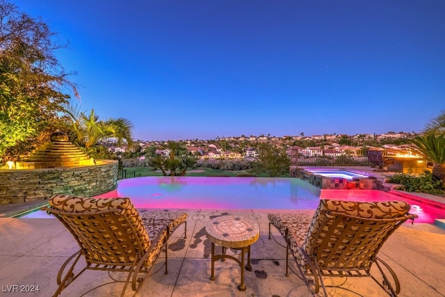 pool at dusk featuring an in ground hot tub and a patio area