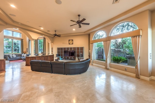 living room featuring decorative columns, a wealth of natural light, and ceiling fan