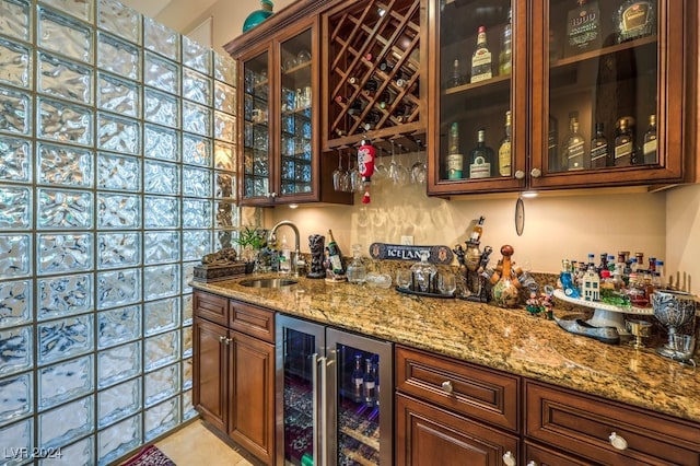 bar with sink, light stone countertops, and beverage cooler