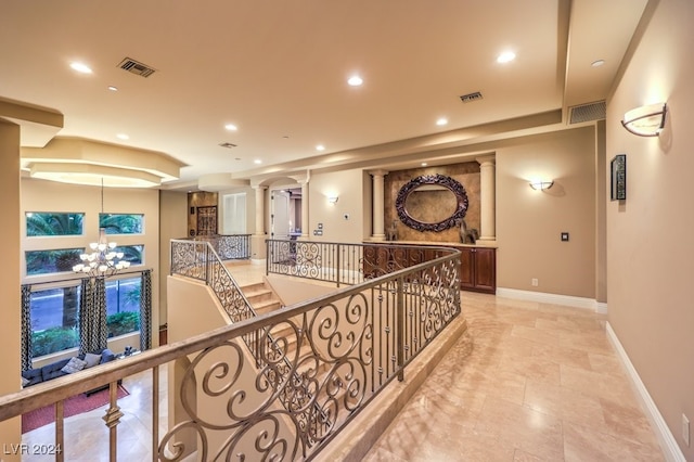 corridor featuring decorative columns and a notable chandelier