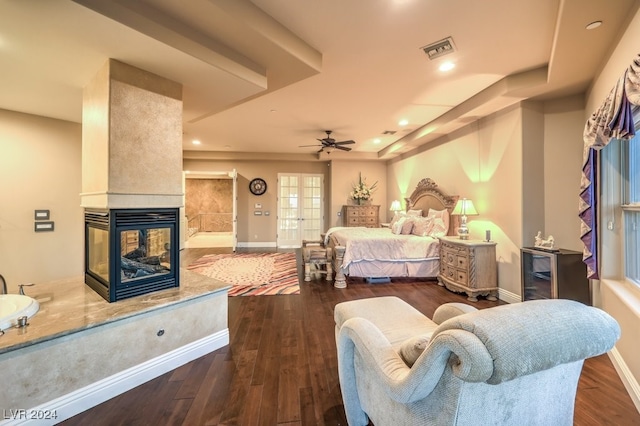 bedroom featuring a multi sided fireplace, hardwood / wood-style flooring, and ceiling fan