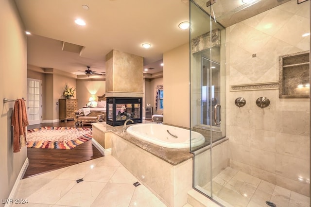 bathroom featuring independent shower and bath, ceiling fan, a multi sided fireplace, and tile patterned flooring