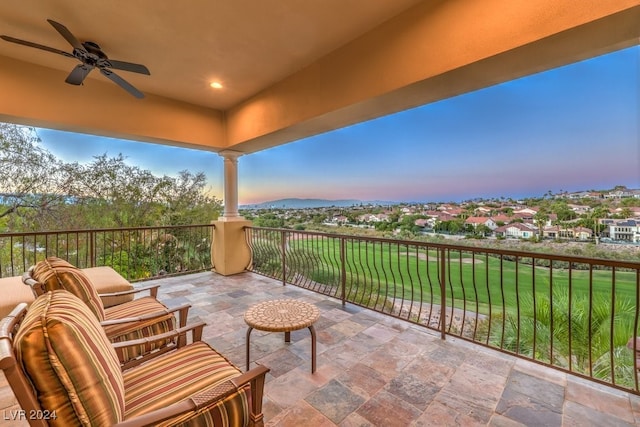 patio terrace at dusk featuring ceiling fan and a yard