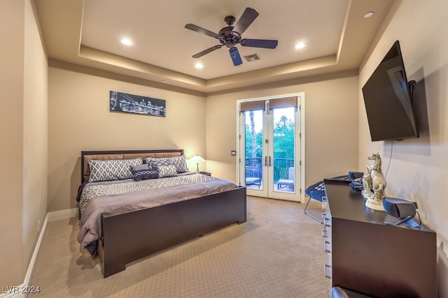 carpeted bedroom with access to outside, a tray ceiling, and french doors